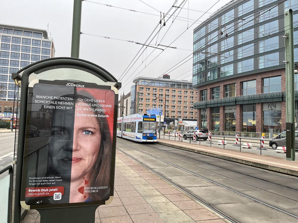 Beleuchtete Citylight-Vitrine an einer Haltestelle mit Plakat