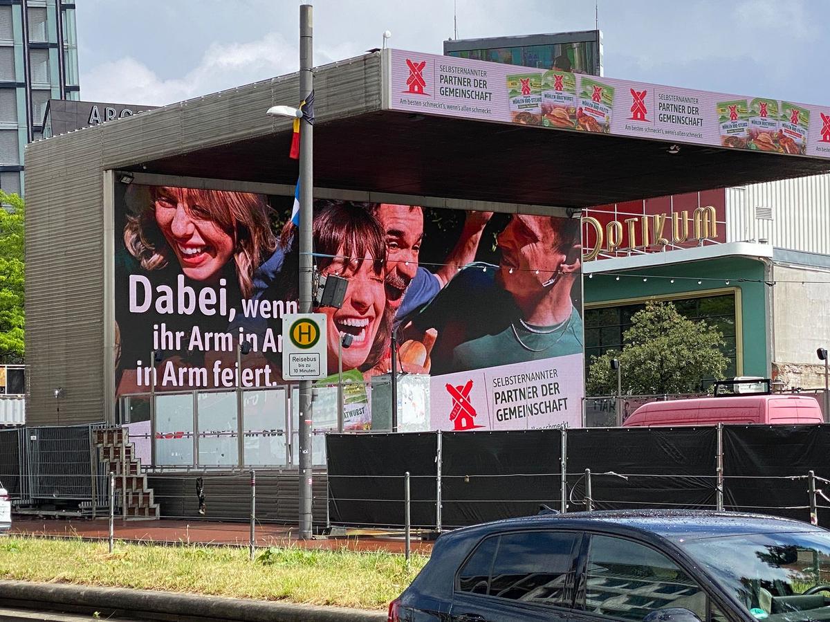 Fassadenbanner an einem Gebäude zwischen Bäumen