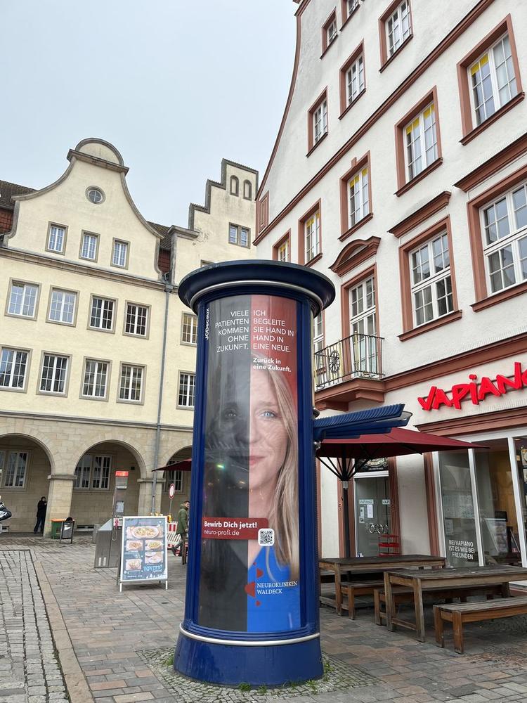 Litfaßsäule mit Plakat auf einem Marktplatz
