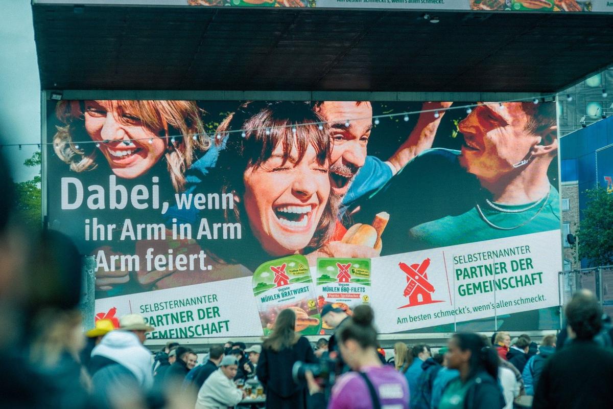 Großes Werbebanner an einer Fassade mit lachenden Menschen